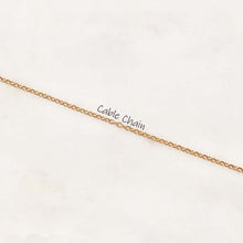 A close-up of a gold cable chain necklace laid diagonally on a light off-white textured background, with the text 'Cable Chain' printed over the center.