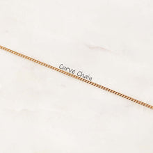 A close-up of a thin gold curb chain laid diagonally across a light off-white marble surface, with the text 'Curve Chain' printed over the center.