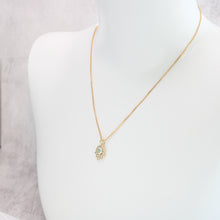 Gold evil eye hamsa hand necklace on a mannequin. 
