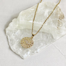 Gold stainless steel Evil Eye rhinestone pendant necklace with sparkling crystal accents details displayed on a natural stone. 