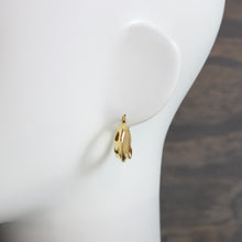 Gold earring on a white mannequin head with a blurred background