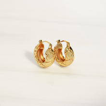 Gold textured stainless steel hoop earrings with polished gold finish, 0.75-inch chunky quilted design and hinged closure.