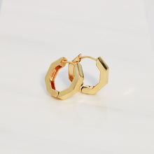 A pair of gold geometric hoop earrings with a polished finish, displayed on a clean white background.