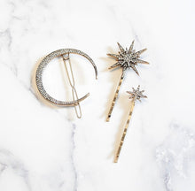 Three-piece celestial hair accessory set with a rhinestone crescent moon hair clip and two crystal star bobby pins in a gold-tone finish.