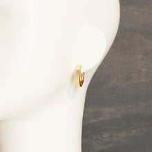 A gold geometric hoop earring displayed on a white mannequin head against a dark gray background.