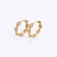 A pair of gold huggie hoop earrings adorned with pavé-set clear stones along the front curve, photographed on a clean white background.