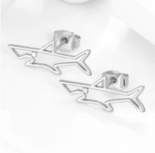 Silver shark stud earrings on a white background. 