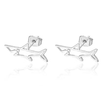 A pair of silver stud earrings in the shape of a shark with sparkling rhinestones, showing the earrings from a side angle.