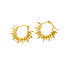 A pair of gold hoop earrings with a sunburst or flame-like pointed design around the lower half, shown on a plain white background.