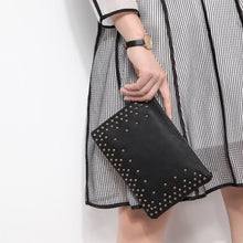 Black gold studded clutch has lined interior, pocket for cell phone, and a zippered pocket. Clutch measures 6 1/2" tall by 9" wide. Made of polyurethane material (faux leather).