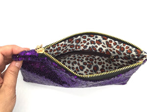 Sequin clutch has a zippered top plus a small zipper pouch on the inside for discreet items. The interior is a leopard vinyl pattern. Clutch measures 9 1/2" wide by 6" tall. Top zipper opening measures 7 1/2" wide. 