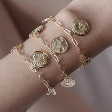 Stackable dainty gold paperclip chain bracelet on wrist.