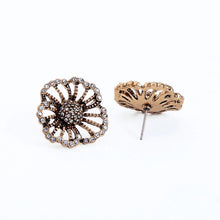 Vintage style rhinestone flower stud earrings with view of post on background. 
